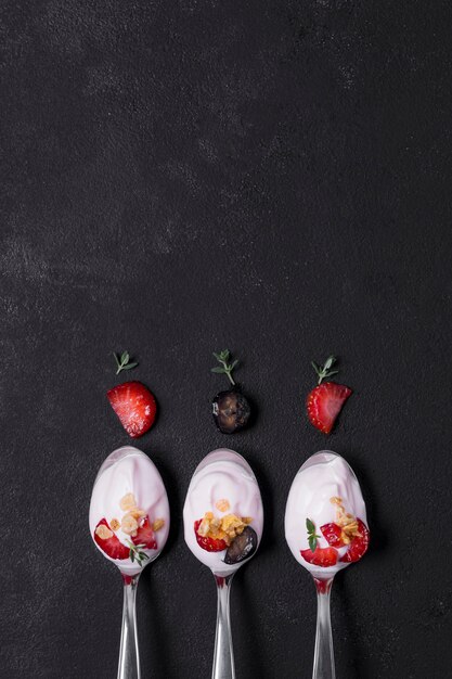 Top view selection of spoons with yogurt and fruits