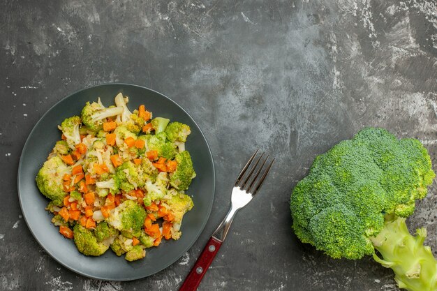 Top view of set of different spices in brown bowls and fresh vegetables on gray background