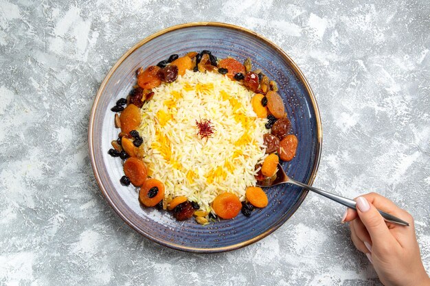 Top view shakh plov cooked rice dish with raisins inside plate on a white space