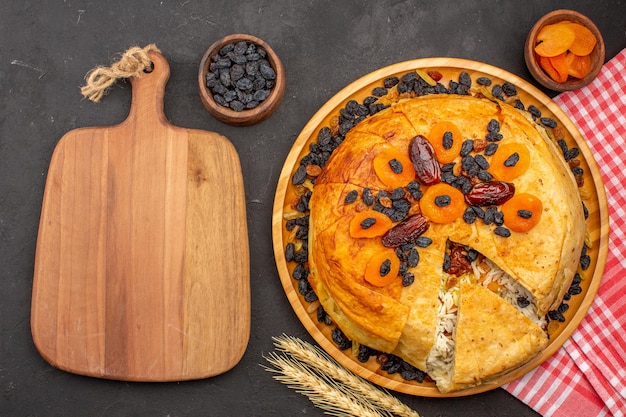 어두운 회색 표면에 건포도와 둥근 반죽 안에 요리 된 shakh plov 맛있는 쌀 식사의 상위 뷰