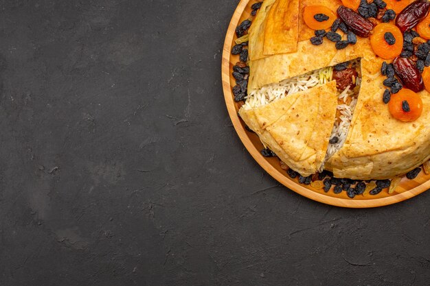 Top view of shakh plov delicious rice meal cooked inside round dough with raisins on a grey surface