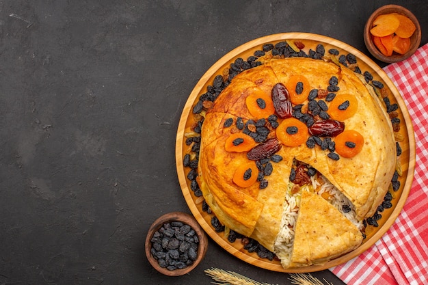 Free photo top view of shakh plov delicious rice meal cooked inside round dough with raisins on grey surface