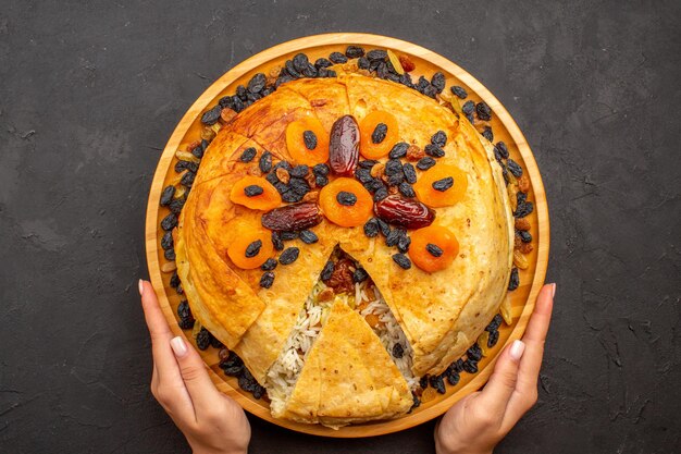 Top view of shakh plov delicious rice meal cooked inside round dough with raisins on grey surface