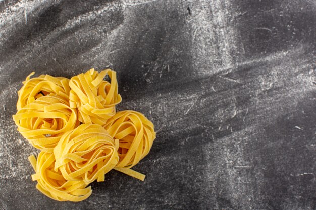 상위 뷰 모양의 꽃 형태의 이탈리아 파스타 회색 배경에 원시 및 노란색 이탈리아 원시 음식 식사 스파게티