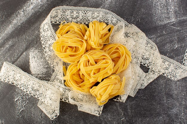 トップビュー形の生パスタと生の黄色のイタリアンパスタグレーの机の上にイタリアの生の食事スパゲッティ