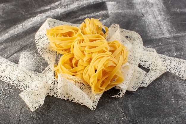 Top view shaped italian pasta in flower form raw and yellow with tissue on the grey background italian raw food meal spaghetti