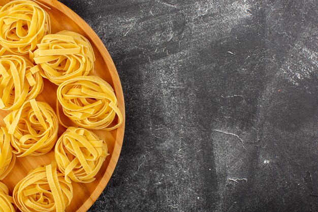 トップビュー形の木製のイタリア料理パスタスパゲッティに生の花と黄色の花の形のイタリアンパスタ