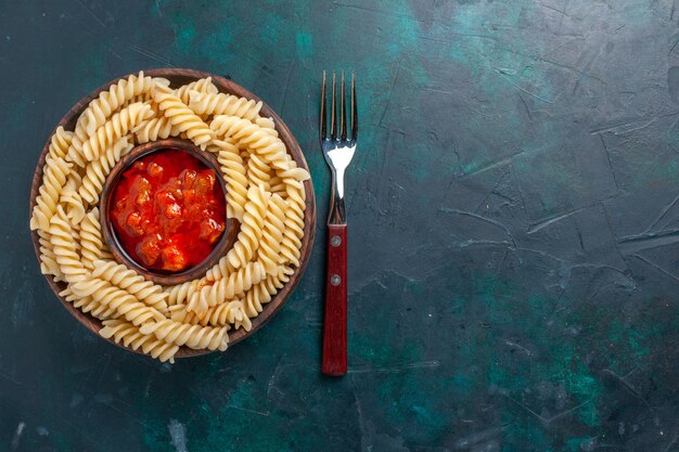 Top view shaped italian pasta with tomato sauce on the dark blue desk