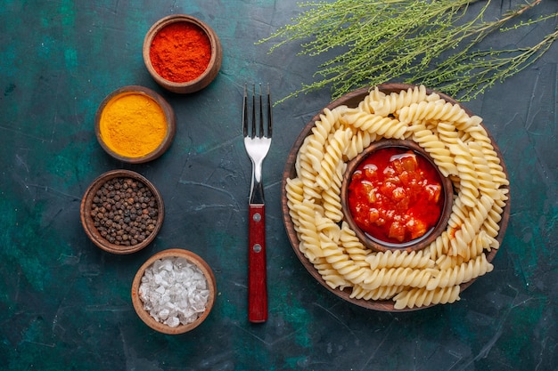 Vista dall'alto a forma di pasta italiana con salsa di pomodoro e condimenti su sfondo blu scuro