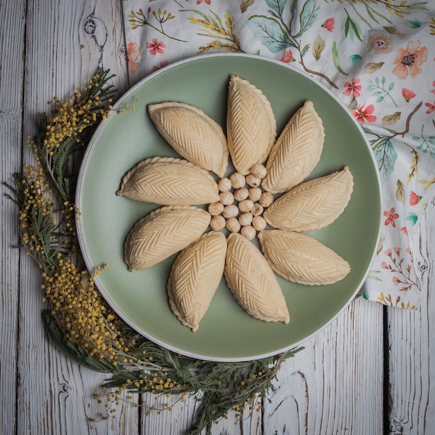 Free photo top view shekerbura with nuts and mimosa flowers in round plate