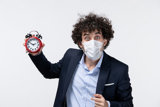 Top view of shocked surprised business person in suit and wearing his mask holding clock