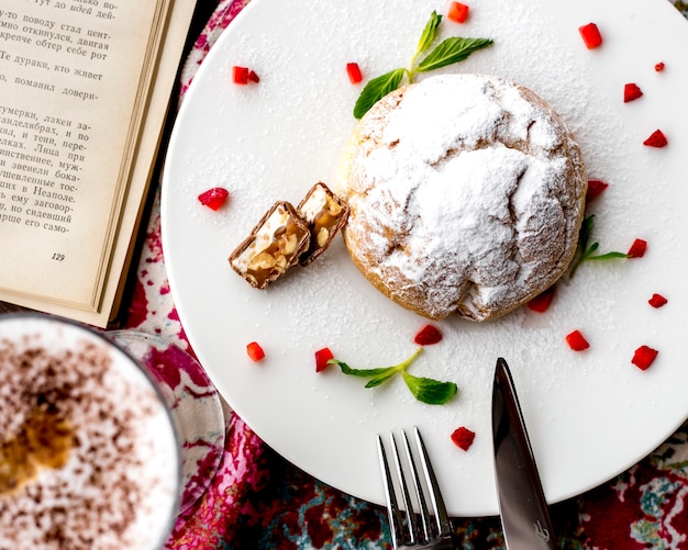 Top view of shortbread dough cake decorated with cutted strawberries on a white plate