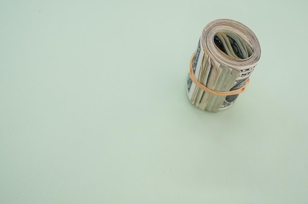 Top view shot of a bundle of rolled-up American banknotes isolated on a light blue background