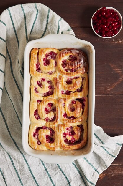 Top view shot of delicious currants snail pastries in a form on a wooden table