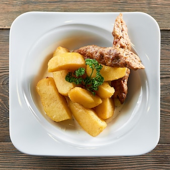 레스토랑 고기 음식 영양 지방 칼로리 식사 메뉴 주문 미식가 봉사 부분에서 제공되는 접시에 구운 감자와 닭고기 소시지의 상위 뷰 샷.