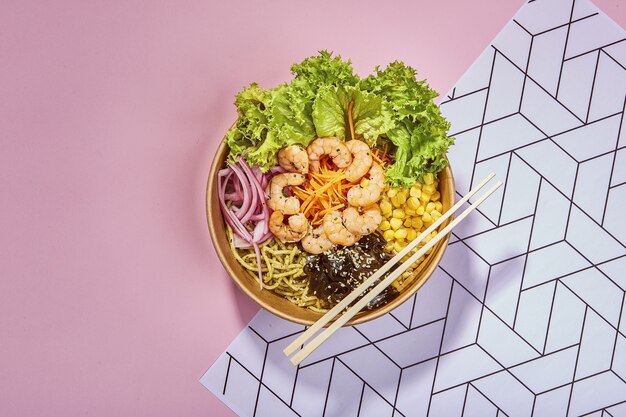 Top view shot of organic poke bowl with chopsticks placed on a textured surface