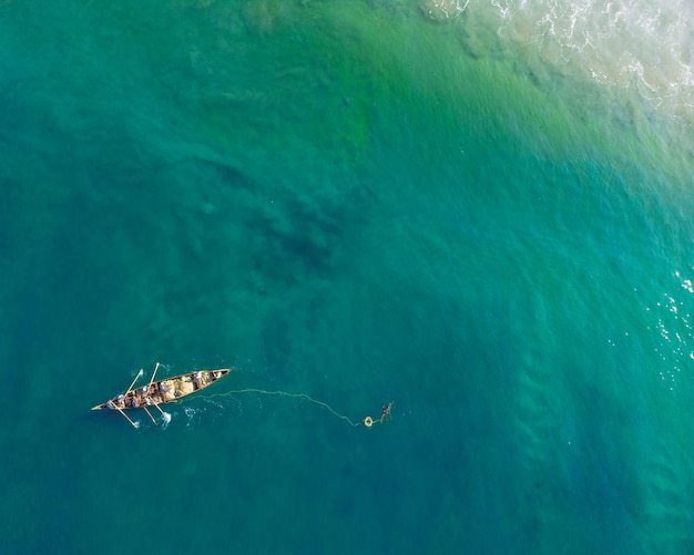 Top view shot of people in a boat fishing in Varkala Beach