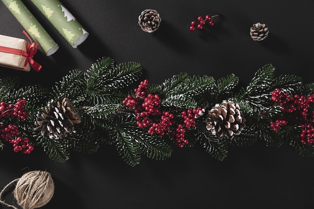 Top view shot of pine branches with cone and gift on a black background