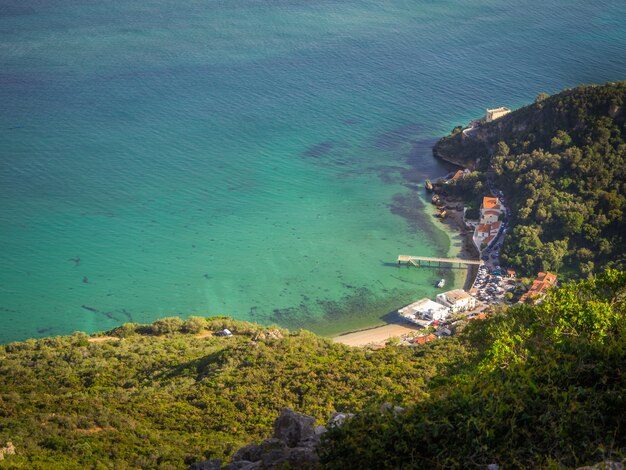 Top view shot of a small harbor next to a forest in Portinho da Arrabida