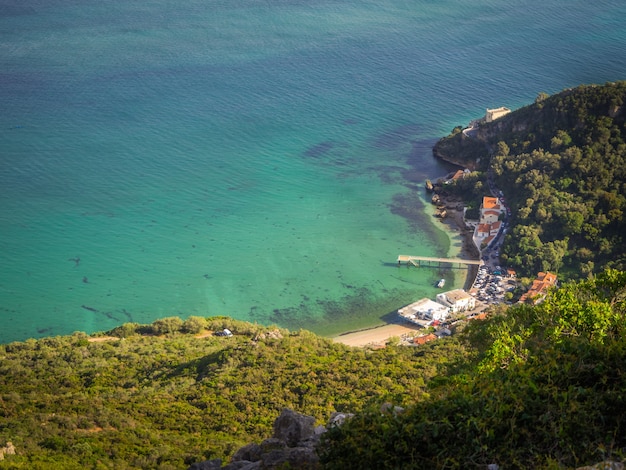 Top view shot of a small harbor next to a forest in Portinho da Arrabida