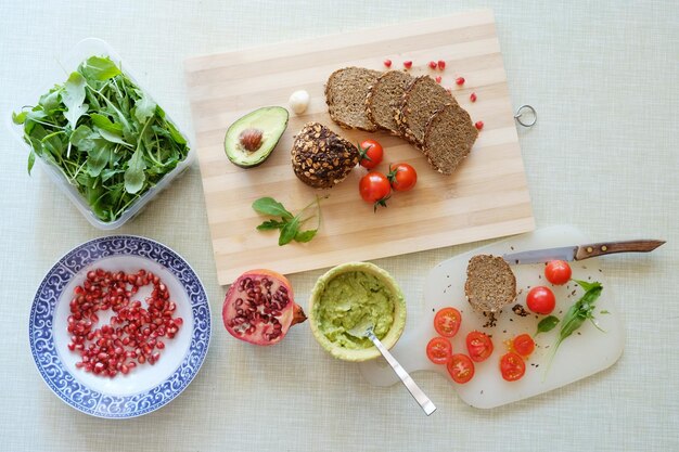 Top view shot of some avocados tomatoes and bread on a cutting board