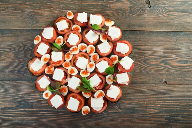 キャビアナストマト野菜健康的な食事食品ダイエットレストランテーブルおいしいグルメで飾られたチーズとゆで卵の皿の上の野菜ミックスのトップビューショット。