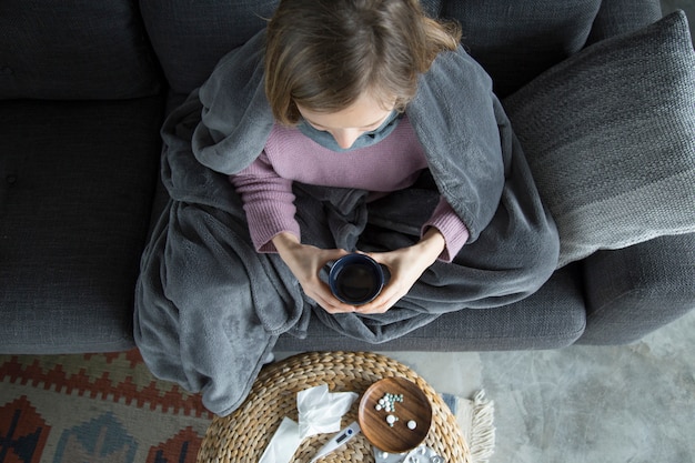 Free photo top view of sick woman at home, holding green cup in hands
