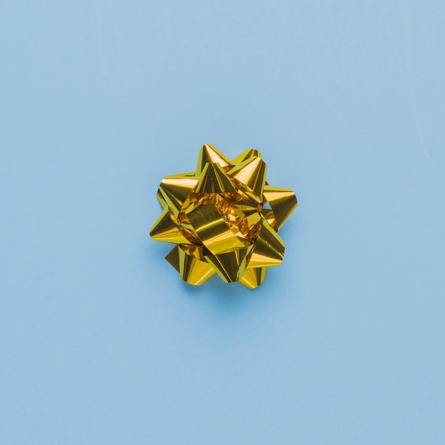 Top view of a single gift bow on plain blue surface