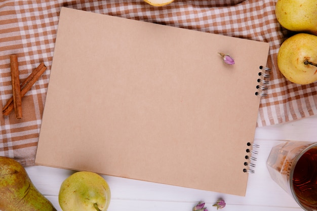 Top view of sketchbook made of craft paper with fresh ripe pears on plaid tablecloth