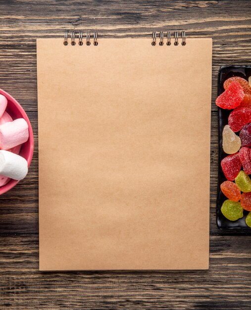 Top view of sketchbook with candies on rustic