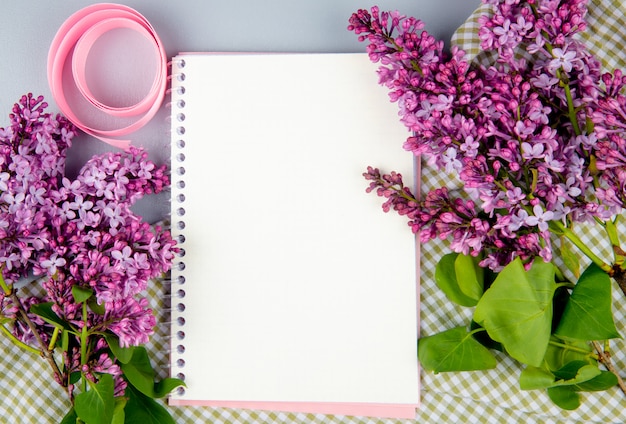 흰색 배경에 격자 무늬 직물에 라일락 꽃과 스케치북의 상위 뷰