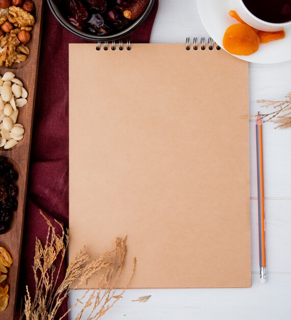 Free photo top view of a sketchbook with mixed nuts and dried fruits on rustic