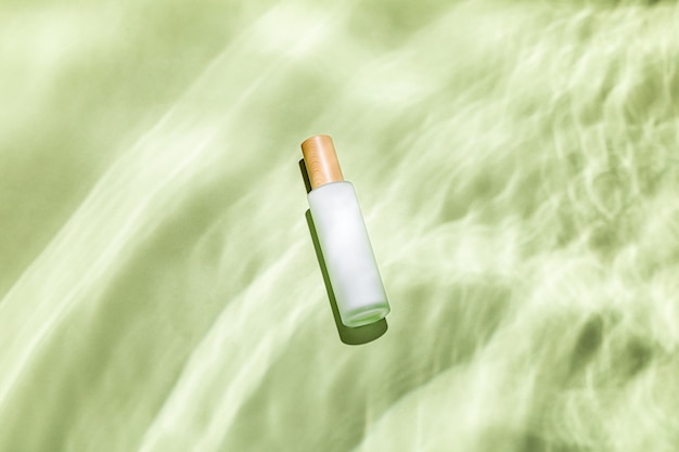 Top view of a skin care bottle on a green textured surface