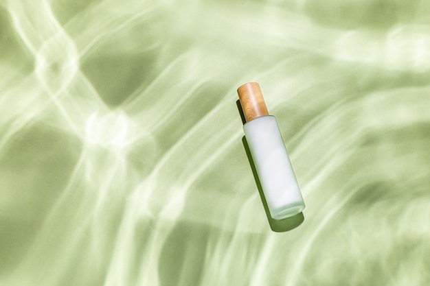 Top view of a skin care bottle on a green textured surface