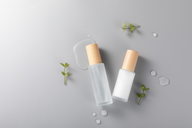 Top view of skincare bottles on a surface with green plants