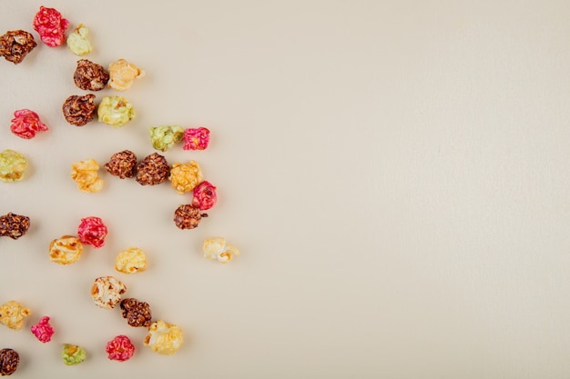 Top view of skittles popcorn on left side and white surface with copy space