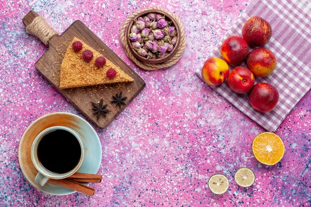 Top view slice of cake baked and sweet with raspberries along with tea and peaches on the bright-pink desk bake sweet cake pie fruit