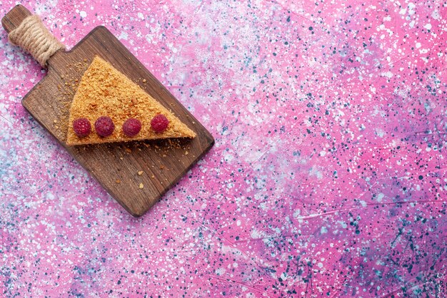明るいピンクの机の上にラズベリーと一緒に焼いて甘いケーキの上面図スライスケーキパイフルーツを焼く