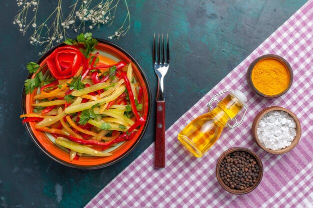 Free photo top view sliced bell-peppers colored spicy salad with seasonings on dark-blue desk