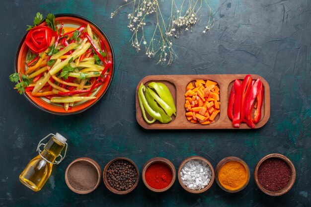 Top view sliced bell peppers healthy salad with olive oil and seasonings on dark blue desk