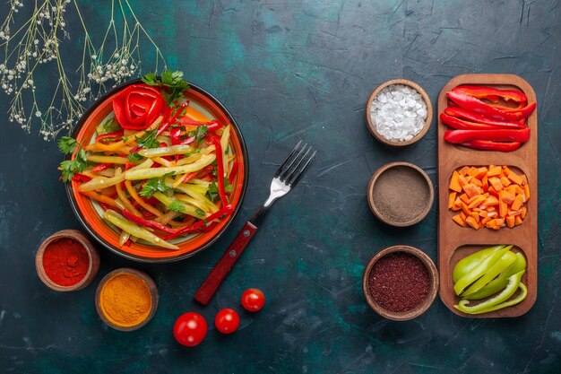 Top view sliced bell-peppers tasty healthy salad with seasonings and other vegetables on dark background