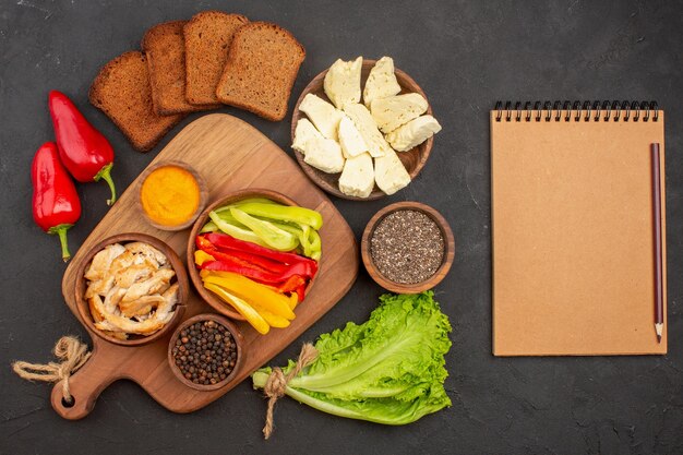 Top view of sliced bell-peppers with dark bread loafs on black