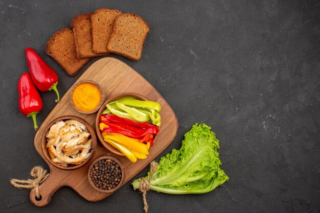 Top view of sliced bell-peppers with dark bread loafs on black