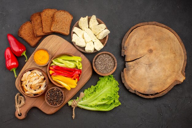 Top view of sliced bell-peppers with dark bread loafs on black