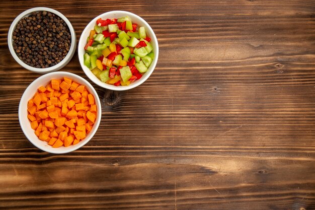 Top view sliced bell-peppers with different seasonings on the brown wooden table vegetable meal food health salad