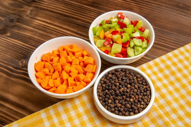 Top view sliced bell-peppers with different seasonings on a brown wooden table vegetable meal health salad