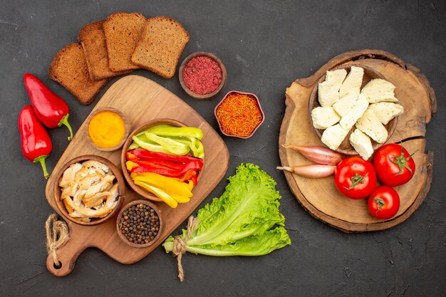 Top view of sliced bell-peppers with seasonings and bread on black