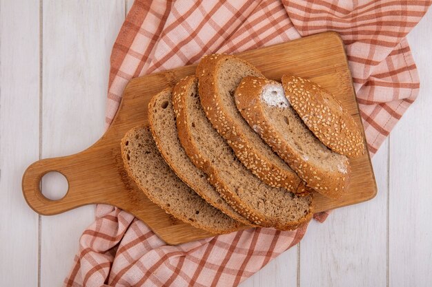 Top view of sliced brown seeded cob on cutting board on plaid cloth on wooden background