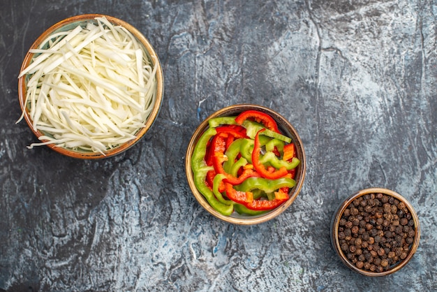 Top view of sliced cabbage with bell-peppers on light-grey surface