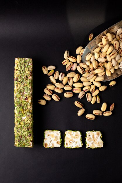 A top view sliced candy bar green yummy sweet along with peanuts on the dark desk